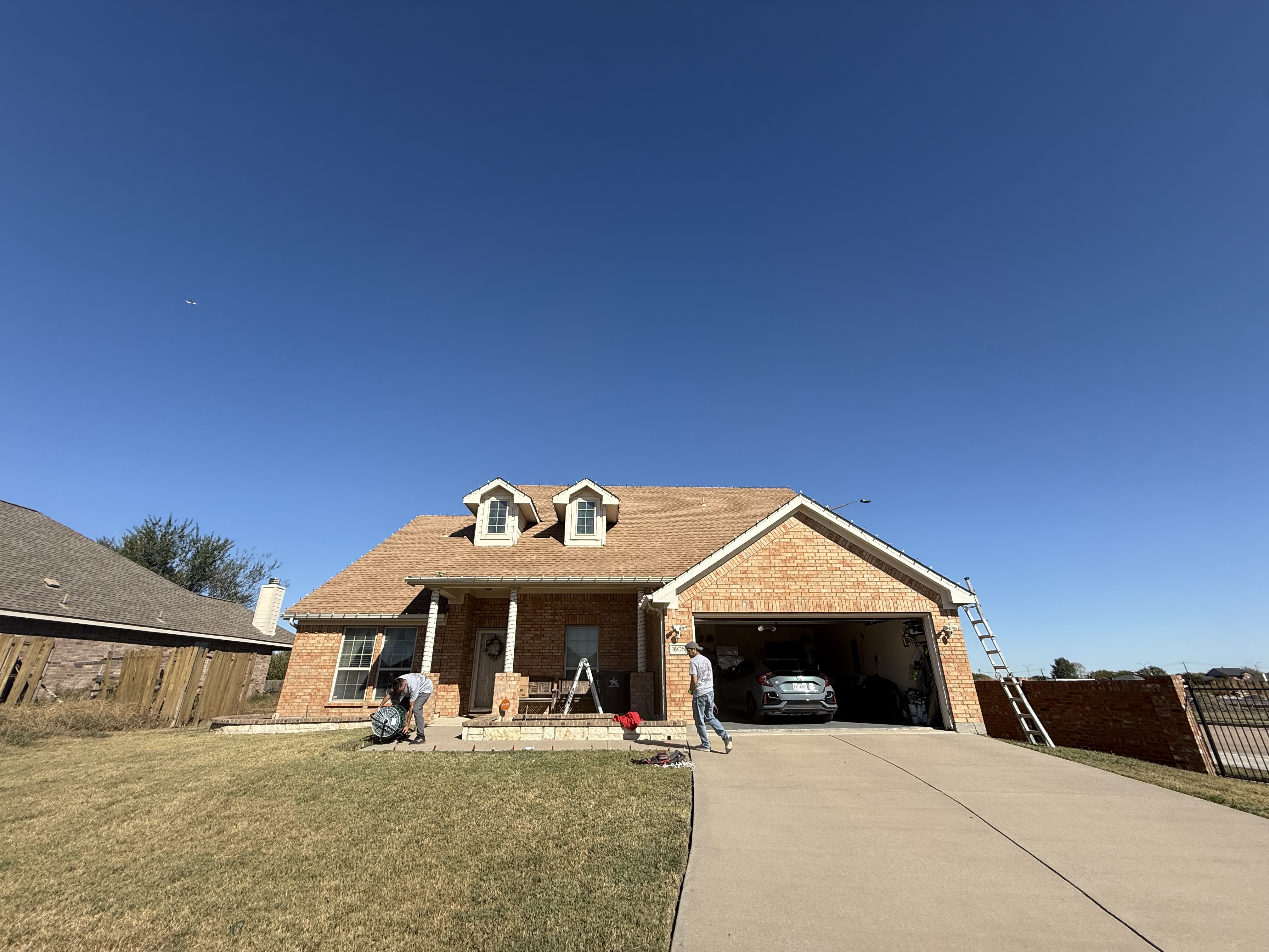 Professional installing lights on single-story brick home