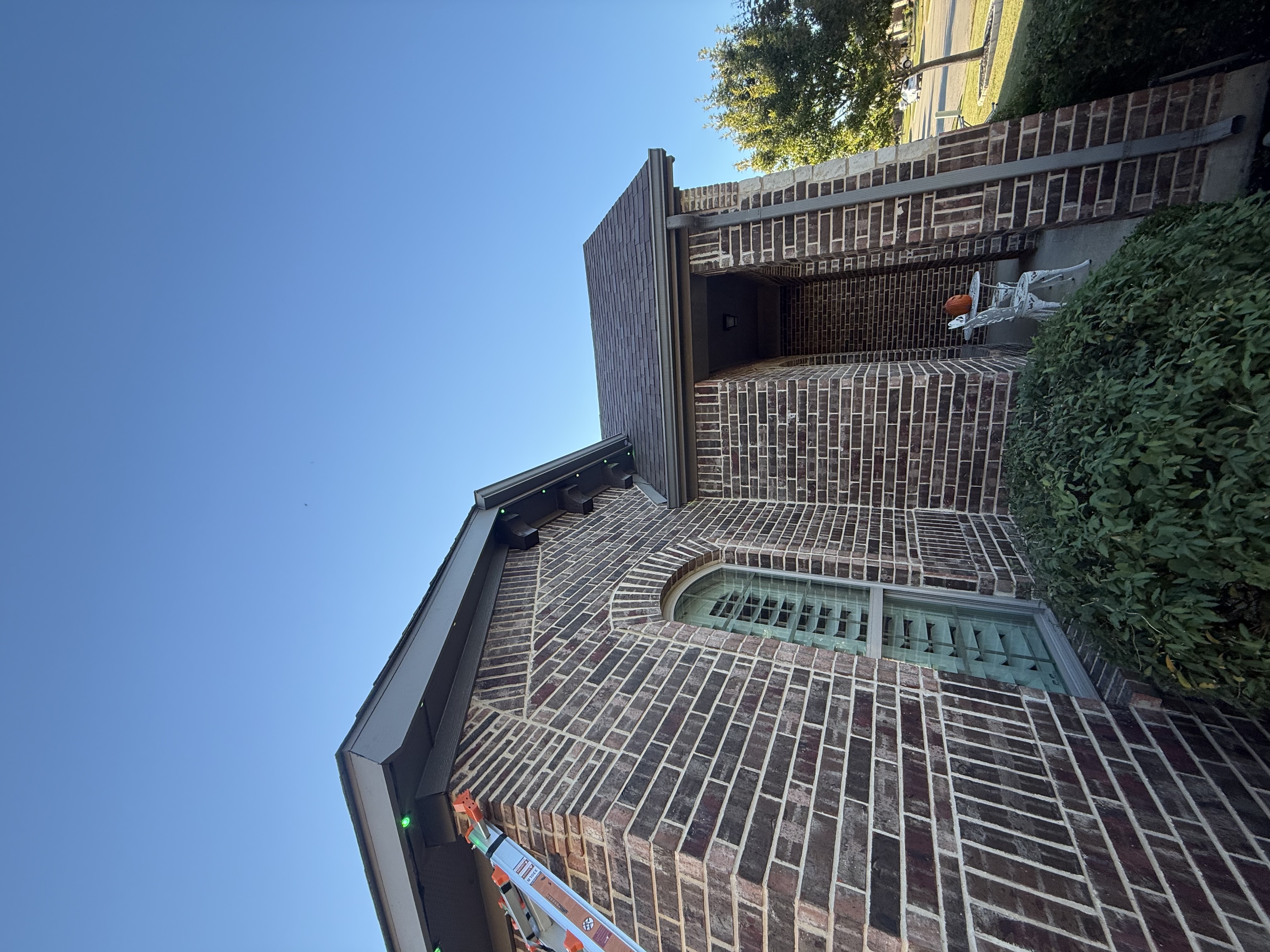 Permanent lighting tracks installed on brick home exterior